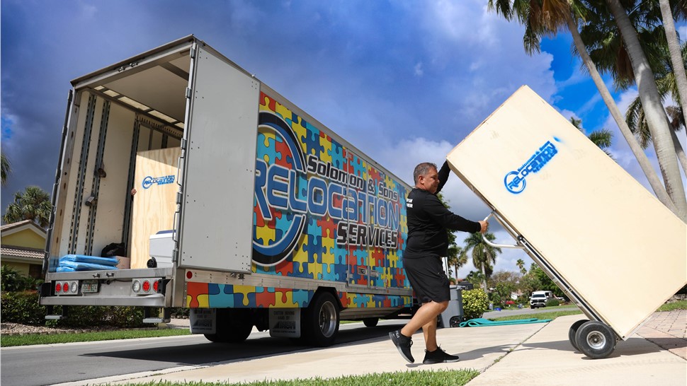 Professional mover unloading furniture from a Solomon & Sons moving truck during a residential move.
