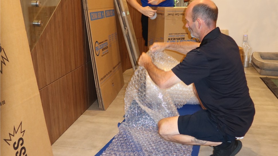 Professional mover carefully wrapping fragile home décor in Miami