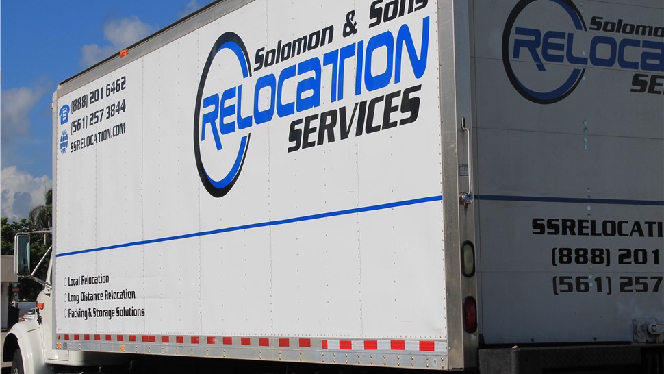 Solomon & Sons Relocation Services moving truck parked outside, showing company branding and contact information.