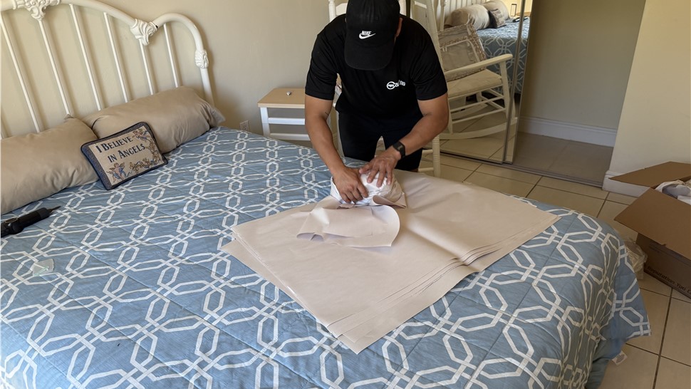 Mover professionally wrapping household items with packing paper in Miami home