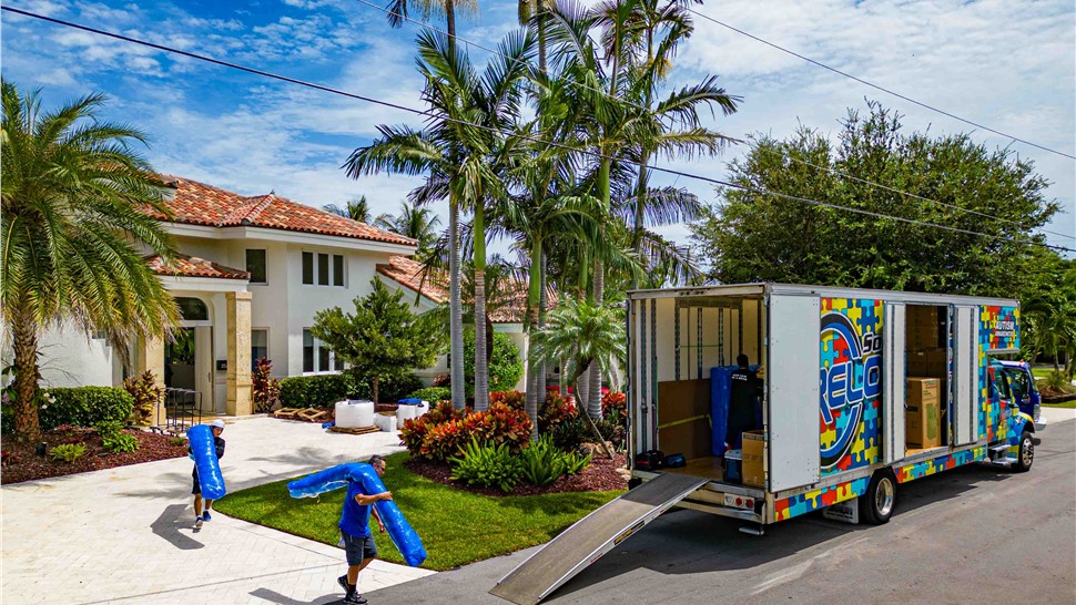 Movers loading a wardrobe box up a ramp into a Solomon & Sons moving truck