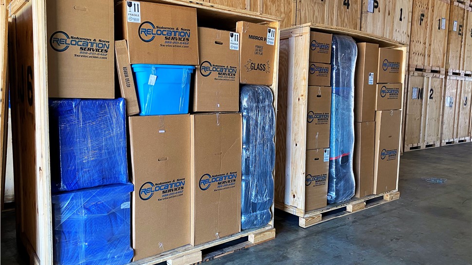 Wood storage vault packed with branded moving boxes and wrapped items for commercial moving and storage.