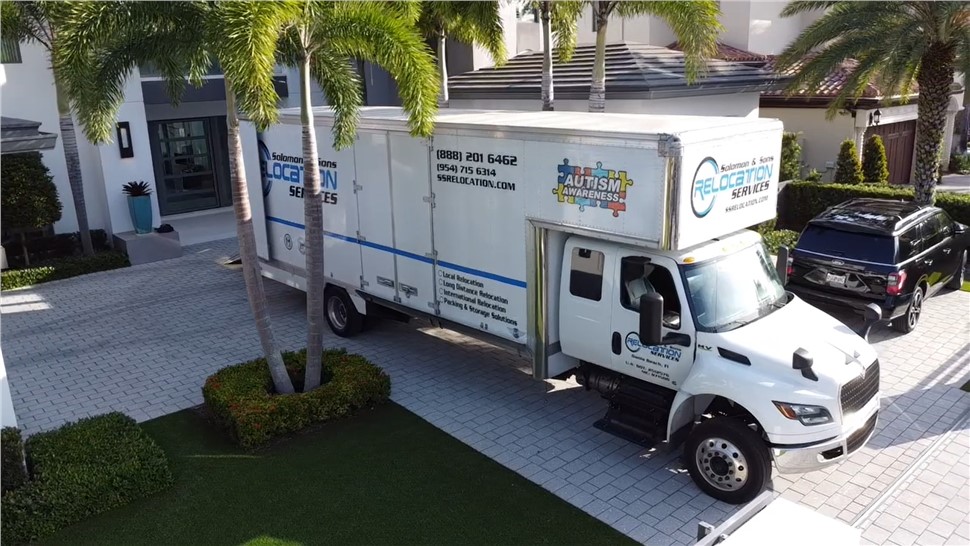 Moving truck parked outside a residential property with palm trees.