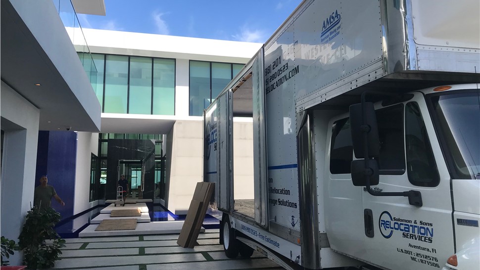Solomon & Sons moving truck parked beside a modern home with the cargo area ready for loading.
