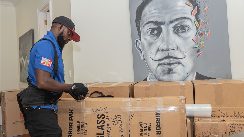 Professional mover packing household items into moving boxes for a residential relocation.