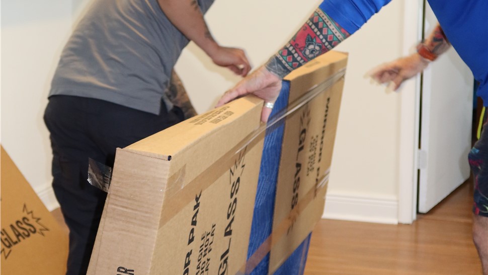 Movers applying protective cardboard and padding to furniture before transportation