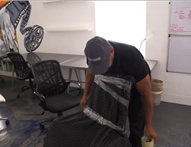 Mover wrapping an office chair with a moving blanket and stretch wrap to protect it during an office move.