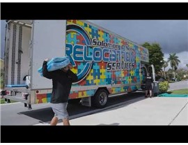 Solomon & Sons mover prepares packing paper and organizes fragile glassware beside labeled moving boxes.