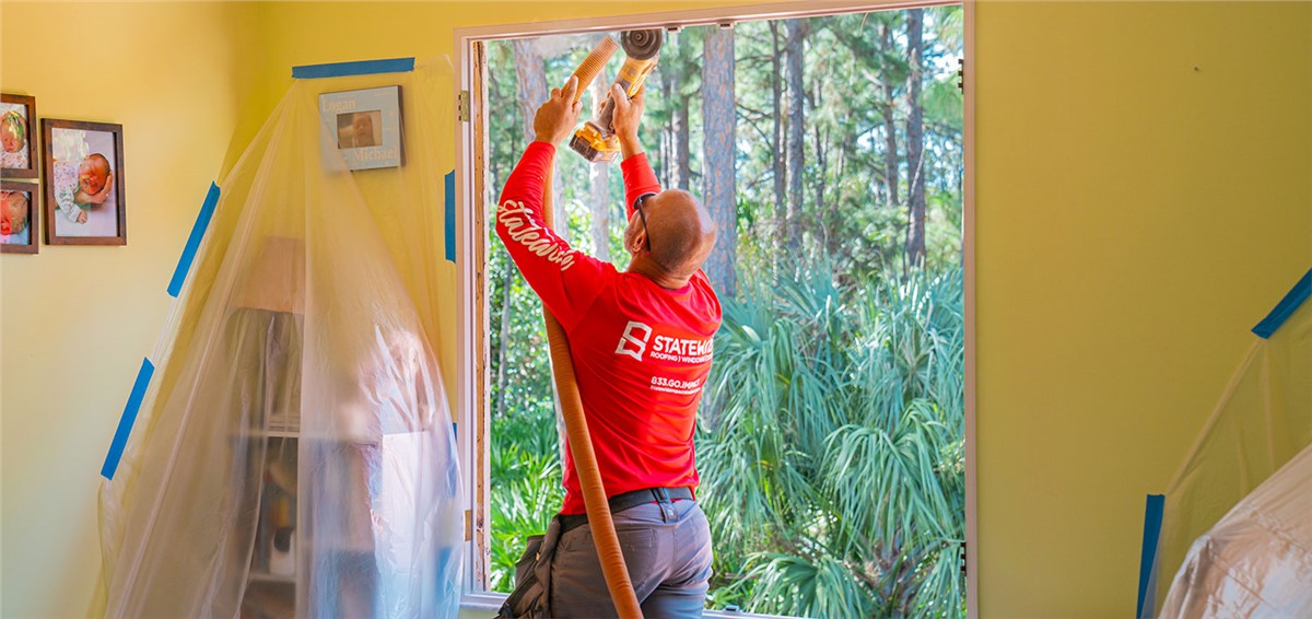 A certified window contractor installing a high-impact window in a residential home.