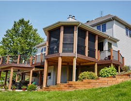 Custom motorized patio screens enclosing a large elevated deck and outdoor living space to provide insect protection, shade, and year-round comfort.
