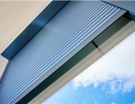 Close-up view of a motorized roll-down screen system showing the housing, track, and retractable screen technology used for outdoor protection.