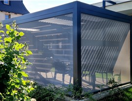 Motorized privacy screen surrounding a backyard patio enclosure, creating a private outdoor living space while maintaining airflow and natural light.
