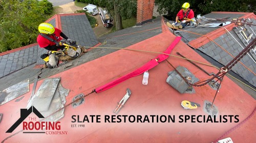 The Roofing Company, Inc. crew performing specialized slate restoration on a multi-story home in Norfolk, fully rigged with certified fall-protection gear.