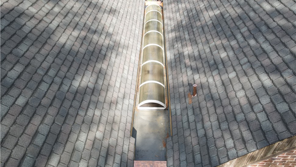 Close-up of a flat roof valley on a Virginia Beach home featuring a robust FiberTite, a long curved skylight, copper edge flashing, and a custom copper plumbing vent pipe collar.