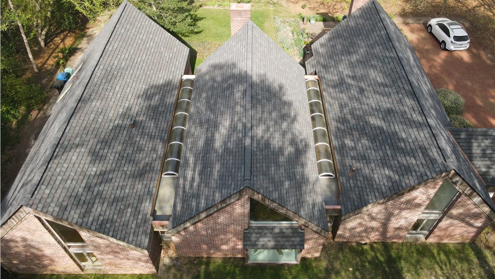Top-down aerial view of a Virginia Beach roofing project highlighting three steep roof peaks covered in GAF Camelot II shingles and two exceptionally long custom skylights in the flat roof valleys.