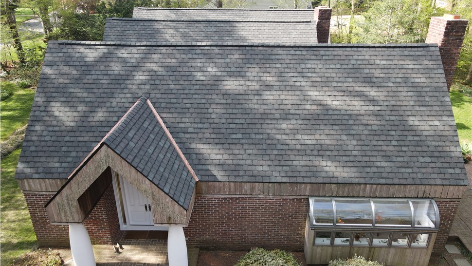 Front view of a custom brick home in Virginia Beach featuring a steep-pitch roof with newly installed GAF Camelot II shingles in Royal Slate and copper flashing on the front entryway.