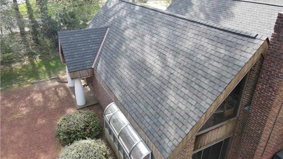 Angled side view of a steep-slope luxury roof installation in Virginia Beach showcasing the elegant Royal Slate color of the GAF Camelot II shingles alongside copper flashing details.