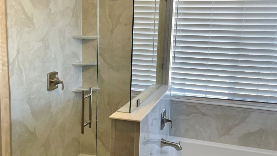 Bathroom shower and tub remodel by Thompson Bath with glass shower enclosure, marble-look walls, and built-in shelving in St. George, UT.