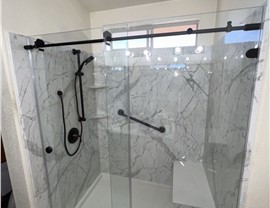 Walk-in shower remodel by Thompson Bath featuring marble-look walls, glass doors, and black fixtures in Las Vegas, NV.
