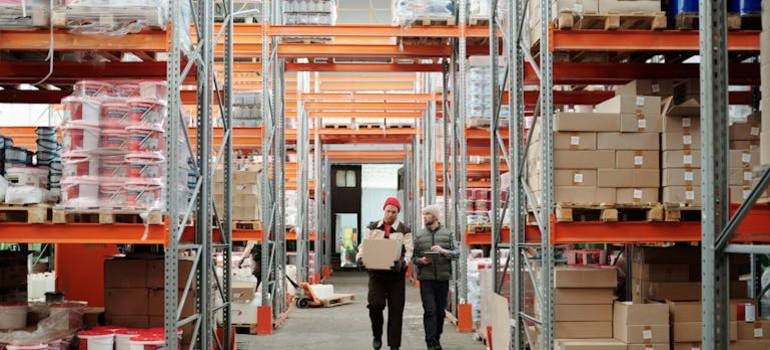 Warehouse workers organizing boxes on high metal shelves during peak season moving in the Bay Area