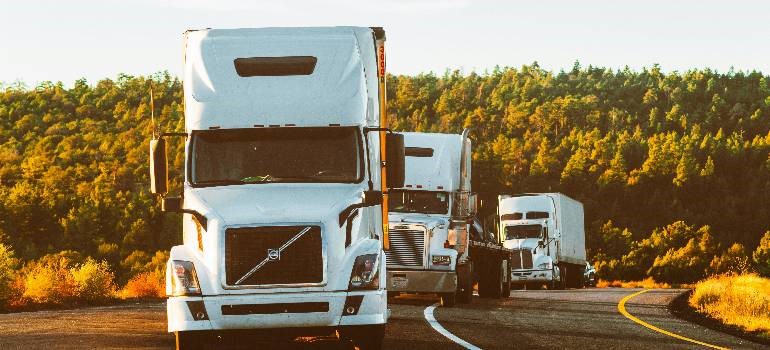 Three moving trucks driving on a curved highway