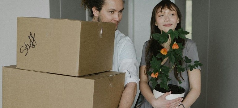 Couple holding plant and moving boxes
