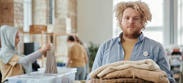 Man carries sweaters to donate unwanted items during a move.
