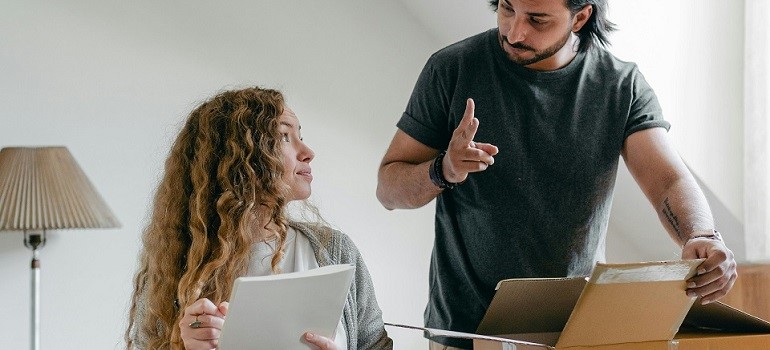 Couple reviewing checklist for your move while packing boxes