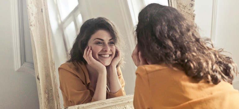 Smiling woman looking at herself in the mirror