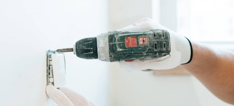 Gloved hand using a power drill indoors
