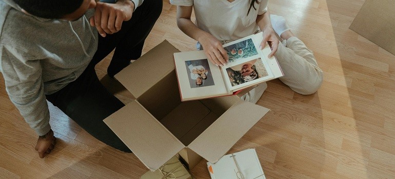 Couple looking at photo album while unpacking as they unpack efficiently in a small San Francisco apartment.
