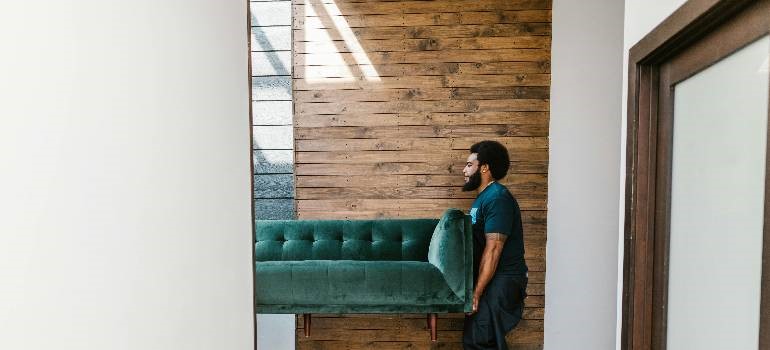Movers carrying a couch to avoid mistakes people make when storing furniture long-term.