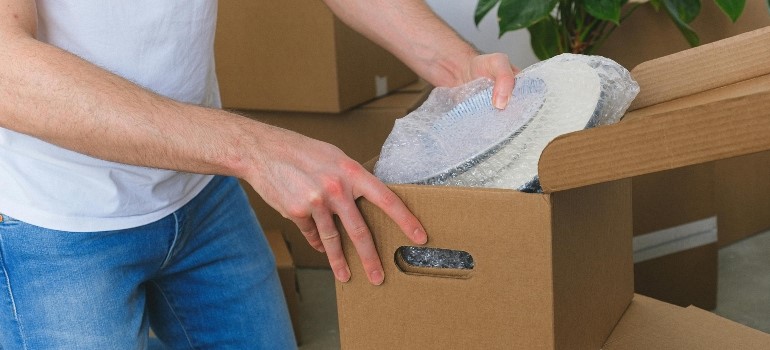 Man packing plates in bubble wrap to move across the Bay Area this spring