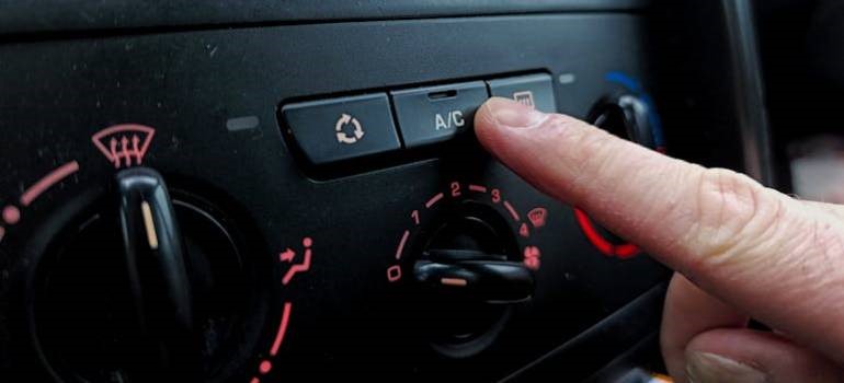 Finger pressing air conditioning button in car