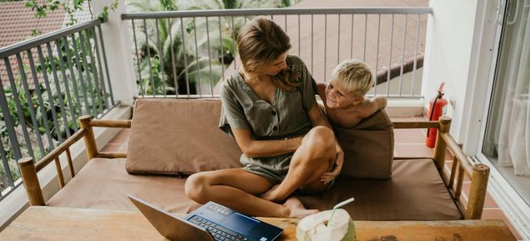 Mother and son sitting with laptop on balcony