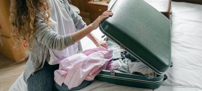 Young woman packing clothes for moving to the big city.