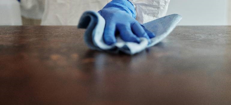 a man cleaning wooden furniture surface before storage to prevent mold.