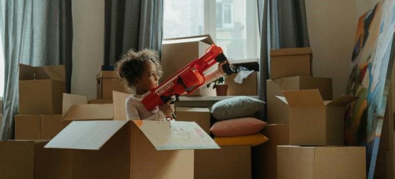 Child playing with toy while sitting in moving box