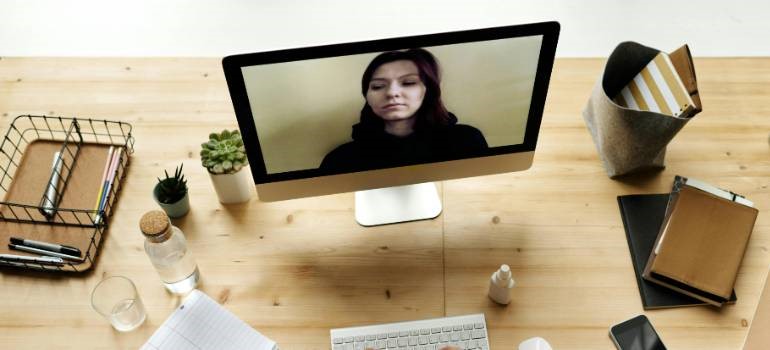 Video call setup on desk with computer and notebooks