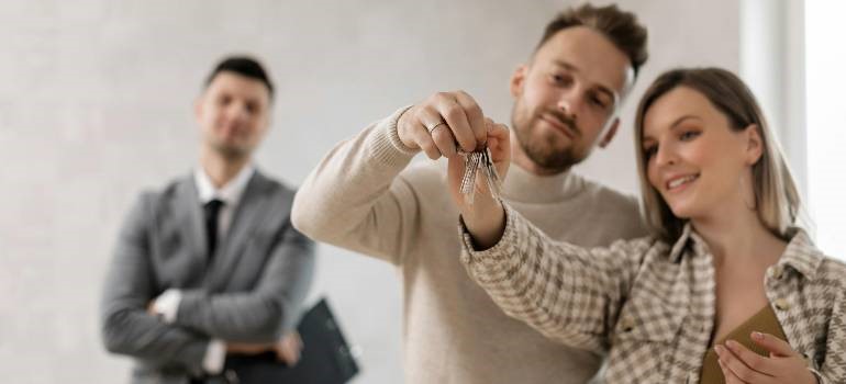 Couple receiving keys from realtor, celebrating the first day after moving to Redwood City.