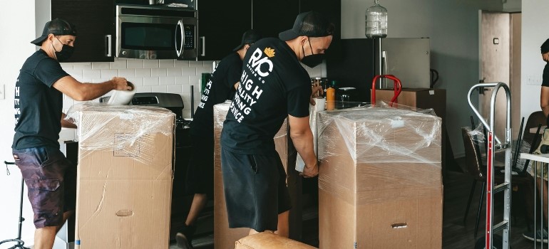 Movers handling moving boxes in a kitchen to move across the Bay Area this spring