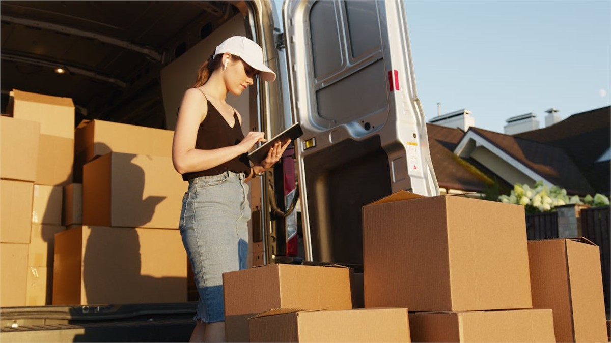 a woman checking some charts in front of the van with boxes and thinking about the Best Time to Move in the Bay Area