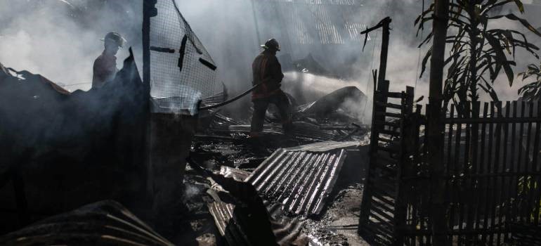 Firefighters controlling smoke and flames after destruction