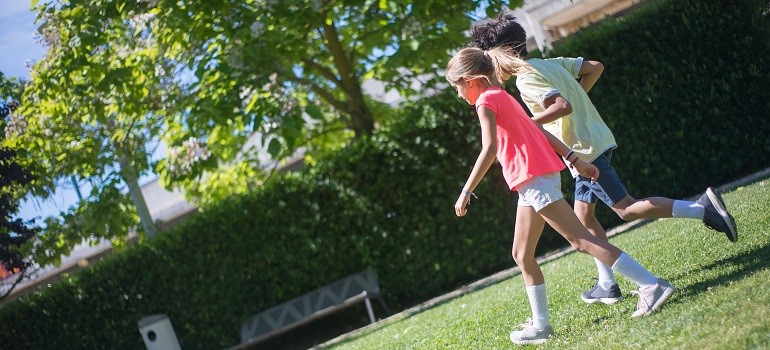 Children running across a green backyard