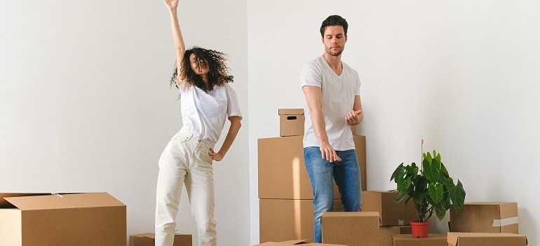 Couple dancing and unpacking boxes together