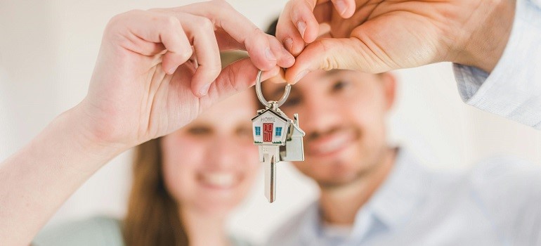Happy couple holding new house keys after move