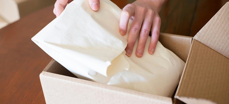 Hands carefully packing box to move large and fragile items