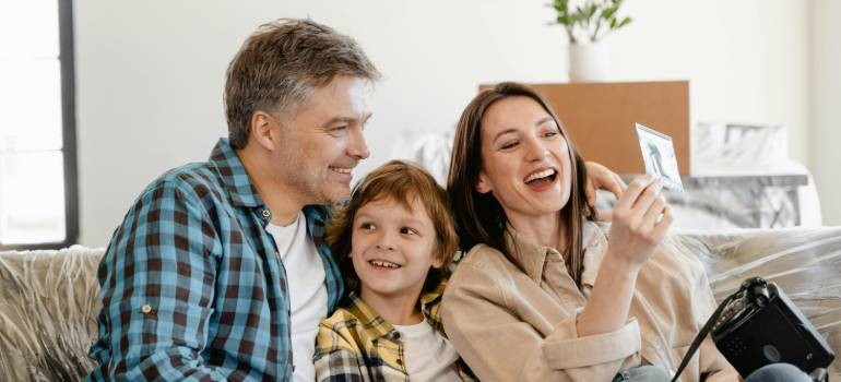 Happy family who knows how to prepare your children for your move looking at photo after unpacking boxes