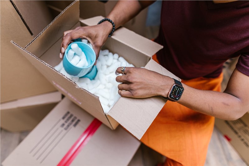 a man packing some mugs in a box 