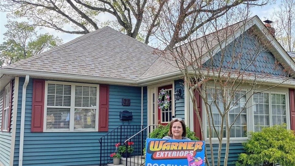 House with newly installed roof by Warner Exteriors with customer sign